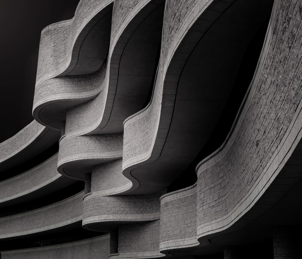 low angle greyscale of a building with modern brutalist architecture under the sunlight